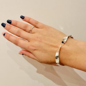 A hand wearing a thin and twisted silver bracelet