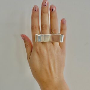 A hand wearing a handmade silver ring shaped as a big swirl.