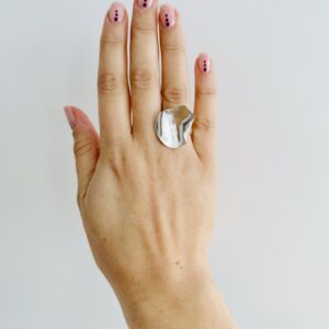 A hand wearing a shiny silver ring shaped as a rose petal.