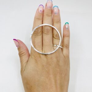 A hand with rainbow coloured nail polished wearing a big silver ring shaped as a twisted circle