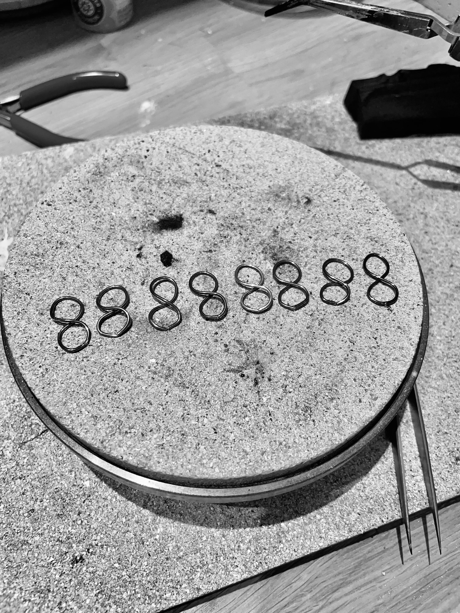 Earrings in the making, shaped as eternity symbols on a silversmith's bench