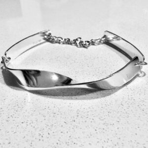 A twisted handmade silver necklace on a white table