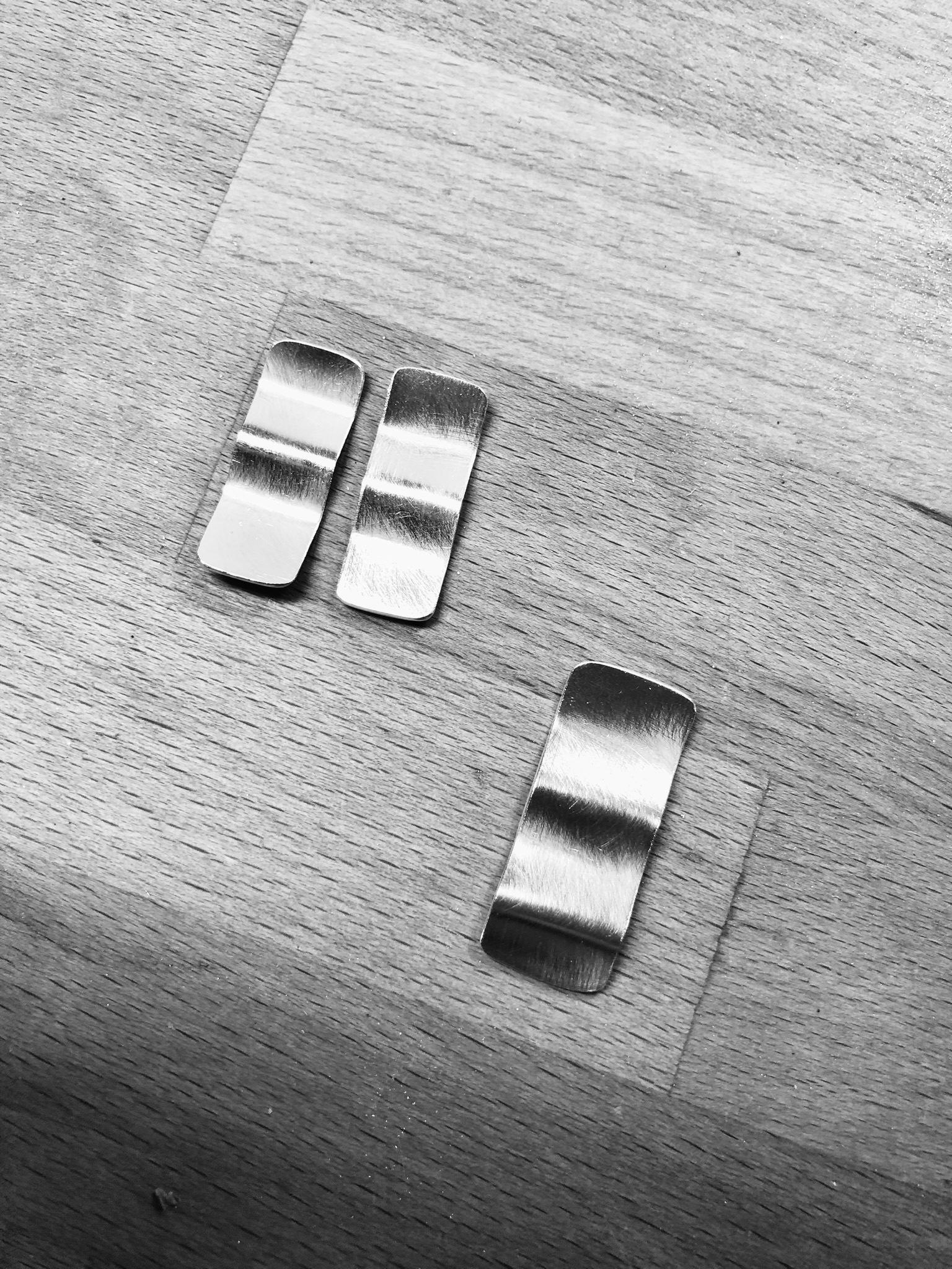 A silverring and a pair of earrings shaped as wavy rectangles.