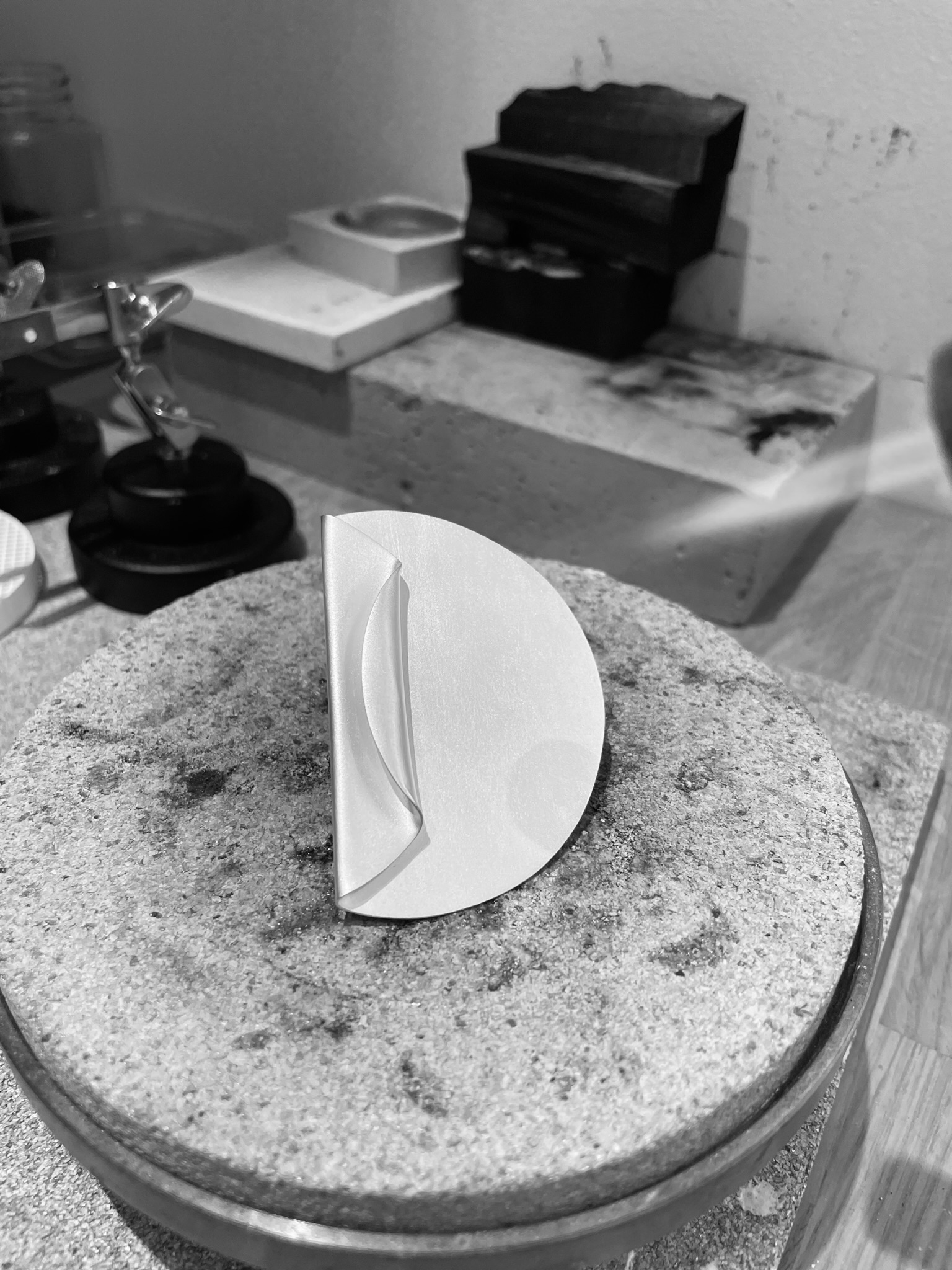 A big ring shaped as a coin with one side folded on a silversmith's bench