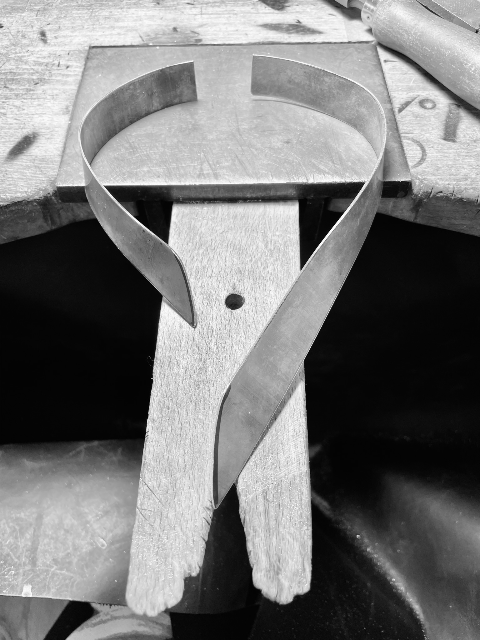 A silver necklace in the making on a silversmithing bench