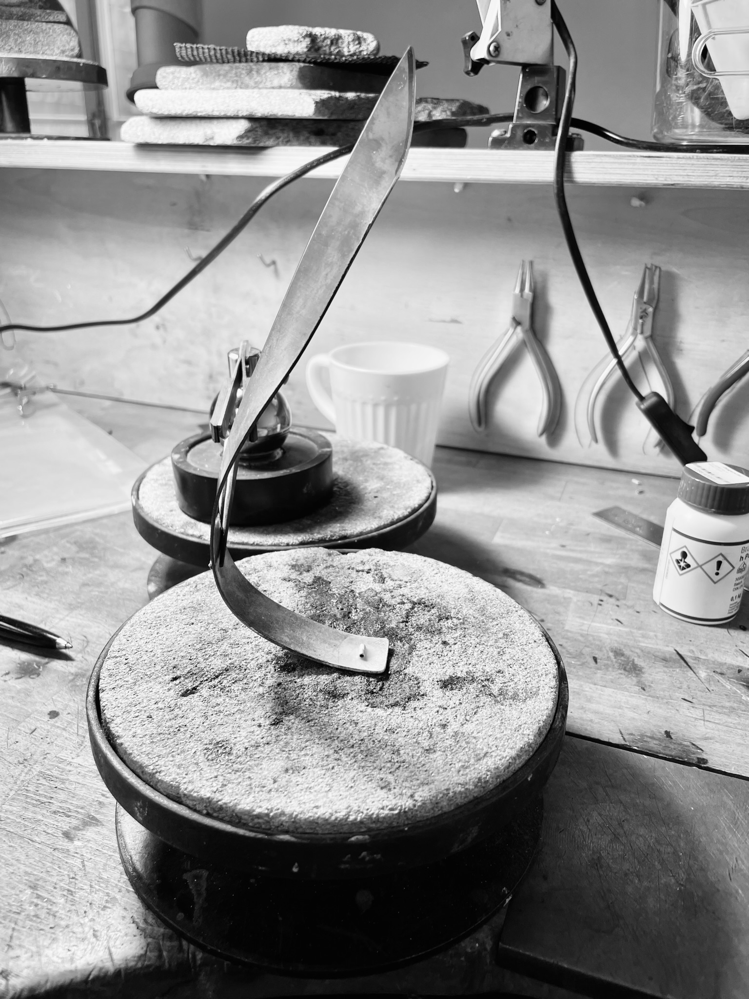 A silver necklace in the making on a silversmithing bench