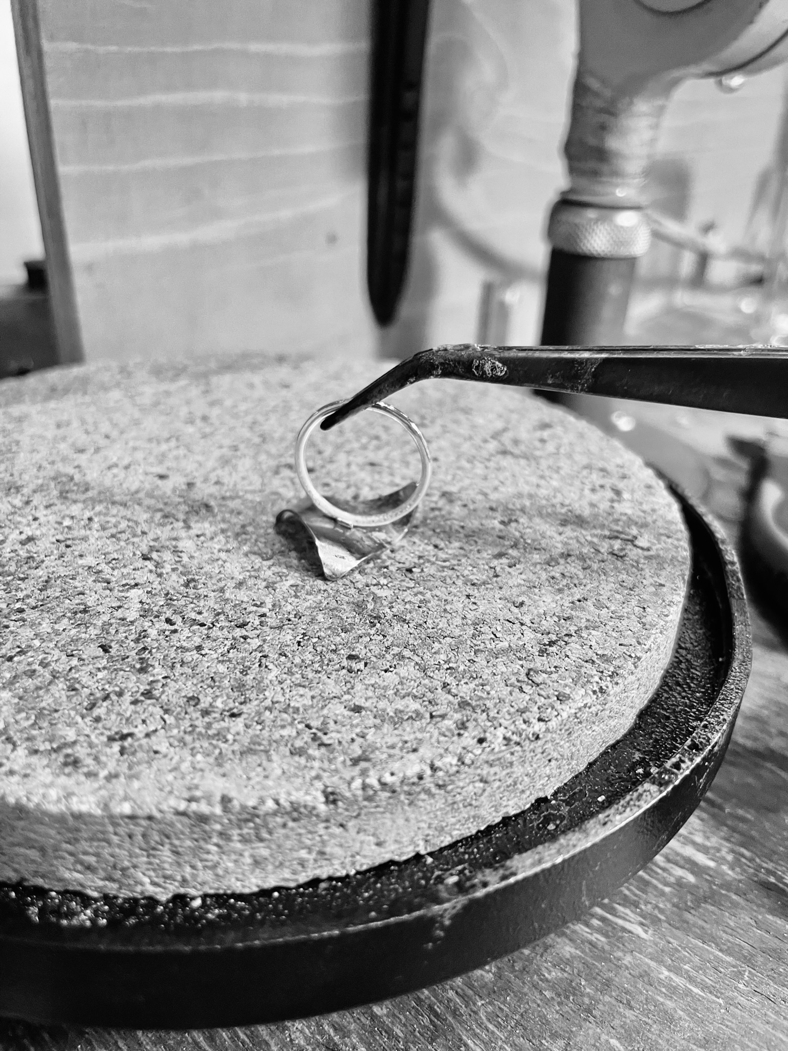 A tweezer holding a ring upside down in a silversmith's studio