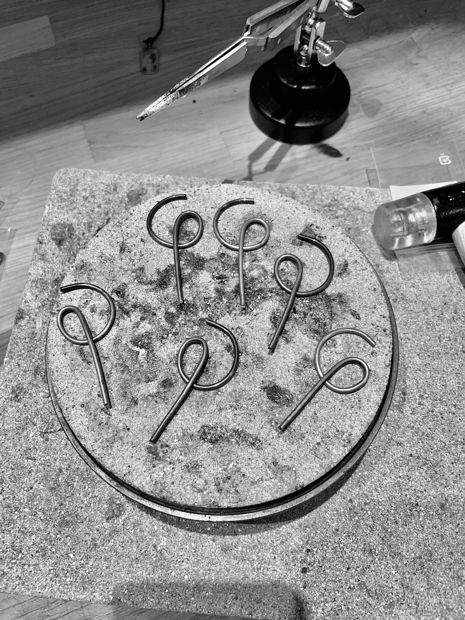 Earrings shaped as venus symbols in the making on a silversmith's bench