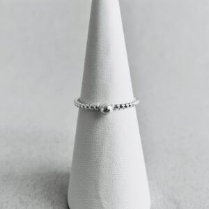 A small thin silverring with a little dot, on a ring holder