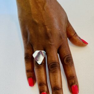 A hand with pink nail polish wearing a silver ring shaped as a wavy traingle